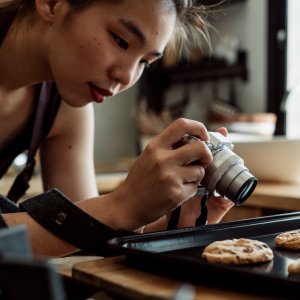 Mujer asiático-americana fotografiando galletas recién horneadas en su cocina.